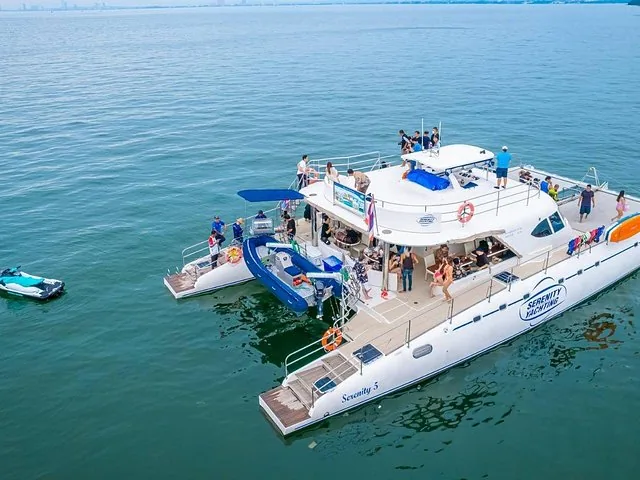 Veduta aerea di un grande catamarano bianco ancorato, con persone che si godono la coperta