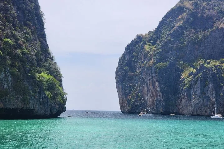 Vue sur l’océan entre deux hautes falaises calcaires à pic, avec des bateaux au loin