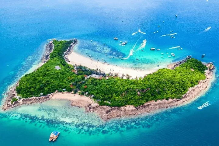 Veduta aerea di un'isola tropicale circondata da acque blu cristalline e diverse barche